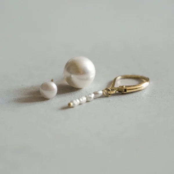 La Mer Pearl Earring in 14-karaats geelgoud. Afgebeeld met de La Mer Pearl Bold Stud en de La Mer Pearl Stud